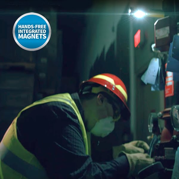 A worker wearing PPE uses the Nightstick XPR-5522GMX Intrinsically Safe Rechargeable Dual-Light™ Flashlight with dual magnets in a dim industrial setting. "Hands-Free Integrated Magnets" is labeled at the top left.