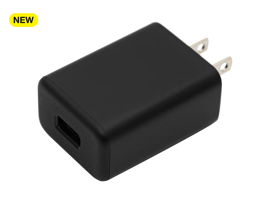 RealWear USB Power Adapter Quick Charge 3.0, a black charger with two prongs, is labeled "NEW" in a yellow box at the top left corner and displayed on a plain white background.
