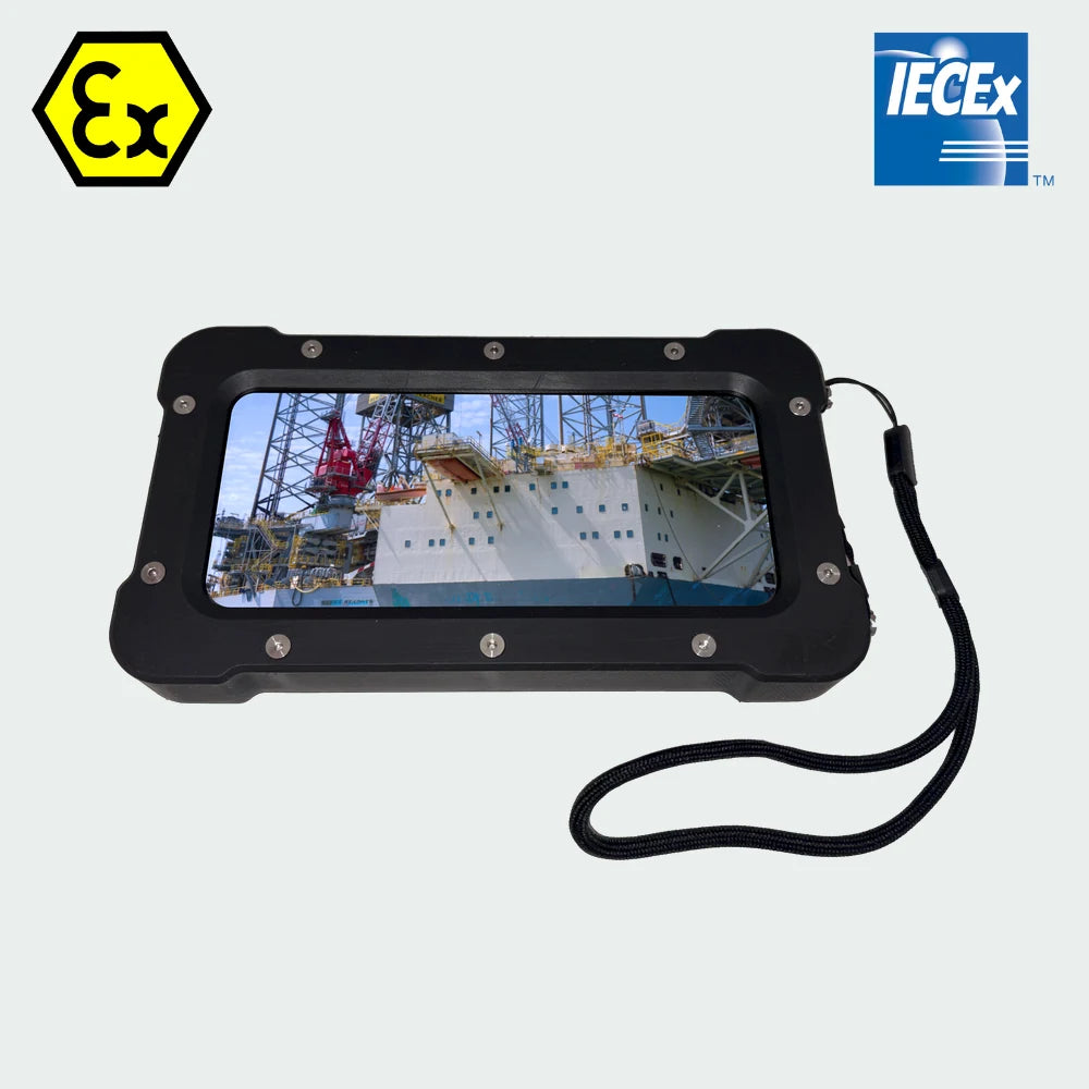 Armadex TCO-60 ATEX/IECEx Zone 2/22 Hazardous Area Inspection Camera with a wrist strap, displaying an image of an offshore oil platform on its screen, flanked by ATEX and IECEx certification logos.