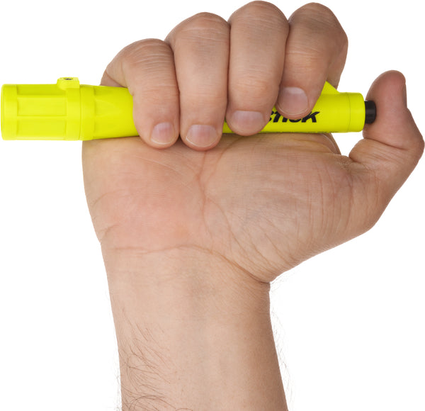 A hand holds a Nightstick XPP-5410G [Zone 0] IS Permissible Penlight vertically, capped and tip pointing up, resembling a yellow highlighter marker.