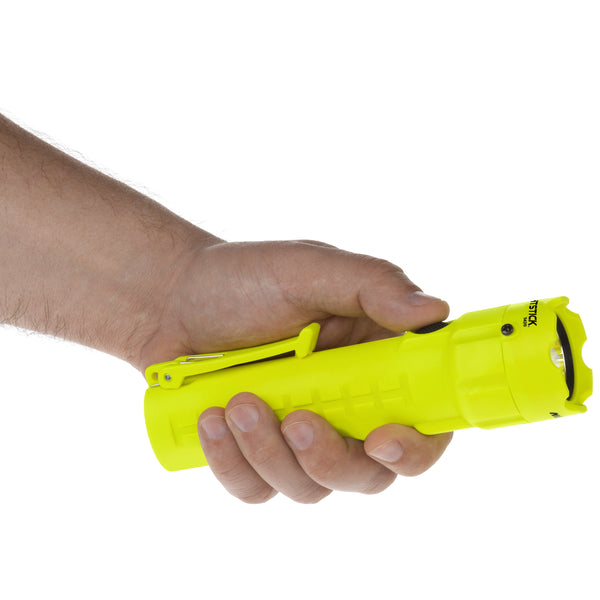 A hand holds a Nightstick XPP-5420G [UL-913] IS Permissible Flashlight, a bright yellow MSHA-listed flashlight with a clip, pointed right against a white background.