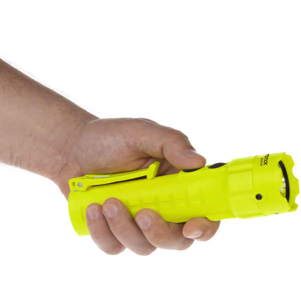 A hand holds the bright yellow Nightstick XPP-5422GA [Zone 0] IS Dual-Light Torch with a clip, positioned horizontally against a white background.