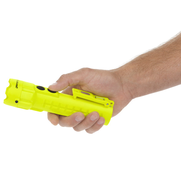 A hand holds the Nightstick XPP-5422GM [UL-913] IS Permissible Dual-Light Flashlight with a clip, black button, and dual magnets.