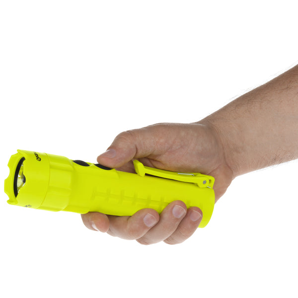 A hand holds a Nightstick XPP-5422G [UL-913] IS Permissible Dual-Light Flashlight, bright yellow with a clip, against a white background.