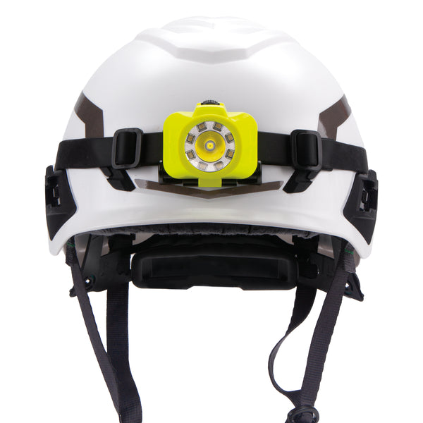 A white safety helmet with a Nightstick XPP-5453G [UL-913] IS Multi-Function Dual-Light Headlamp and adjustable black straps, shown from the front.