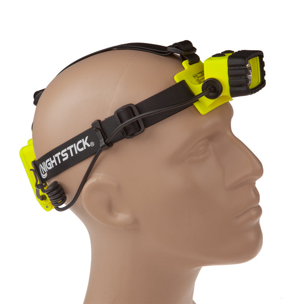 A mannequin head wears the Nightstick XPP-5456G [Zone 0] IS Permissible Dual-Light Headlamp, a yellow and black waterproof industrial flashlight with adjustable strap, forehead light, and rear battery pack—built for tough environments.