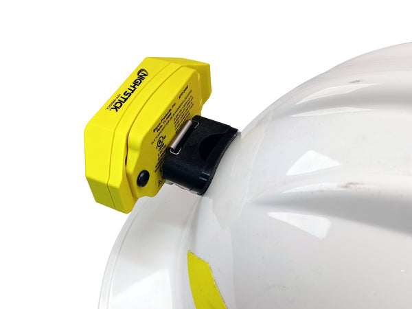 A Nightstick XPP-5460GCX [Zone 0] IS Low-Profile Dual-Light Headlamp is securely mounted on the side of a white hard hat, which has minor scuff marks.