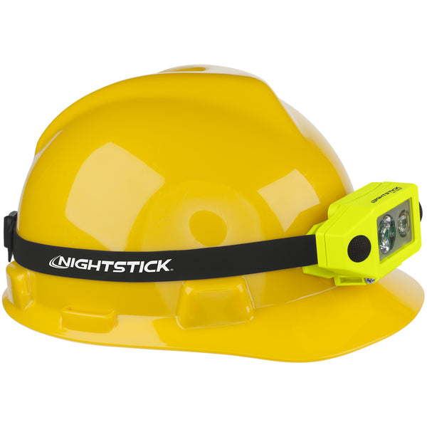 A yellow hard hat featuring a black "NIGHTSTICK" headlamp strap and a Nightstick XPP-5460GX [Zone 0] IS Low-Profile Dual-Light Headlamp in bright yellow attached to the front left side.