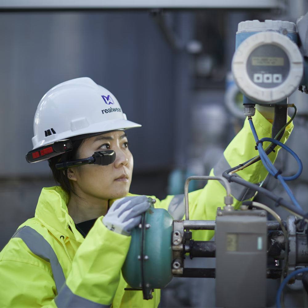 A worker in safety gear and a hard hat operates industrial equipment while wearing the RealWear Navigator Z1 with Thermal Camera, intrinsically safe smart glasses.